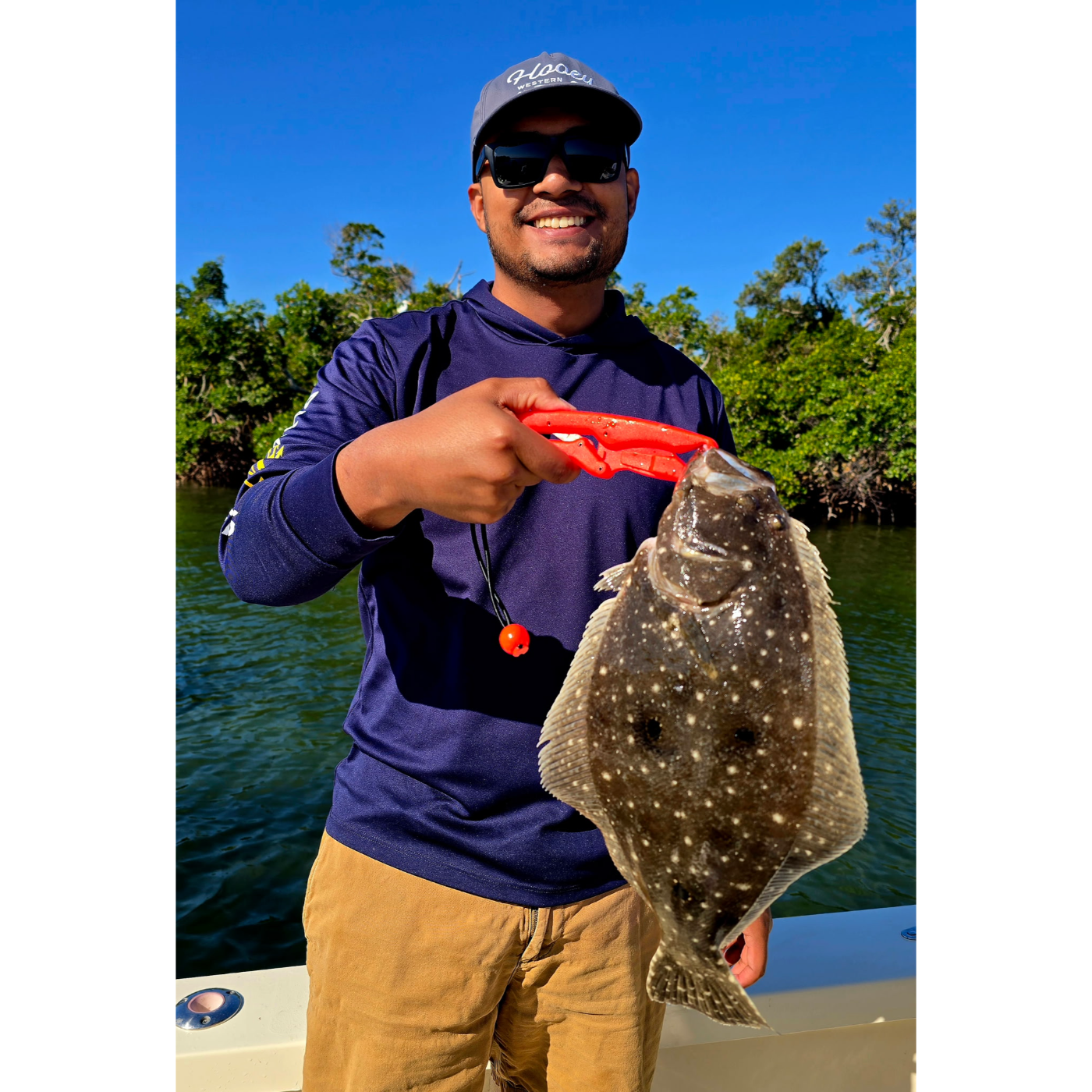 Man holding a fish caught on a fishing line with a scenic background