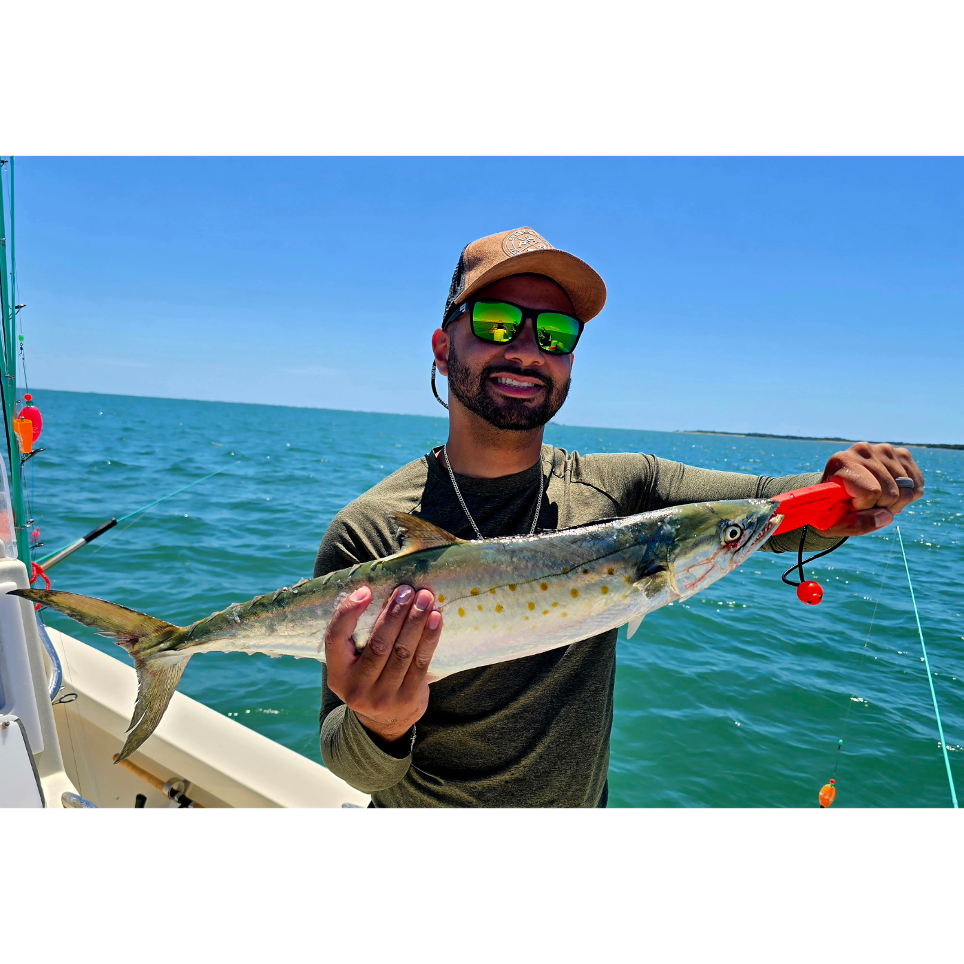 Man holding a fish on a boat with a clear blue sky and ocean background